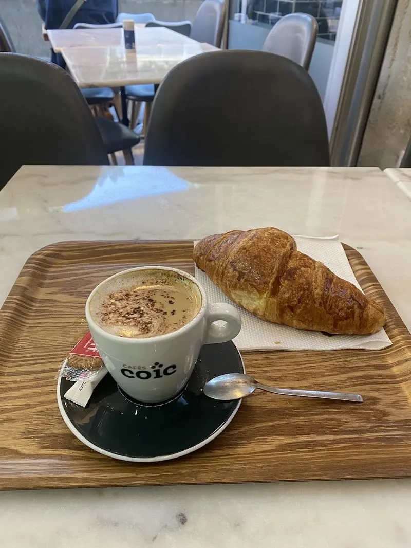 Café et croissant servis sur un plateau en bois chez Friends Burger